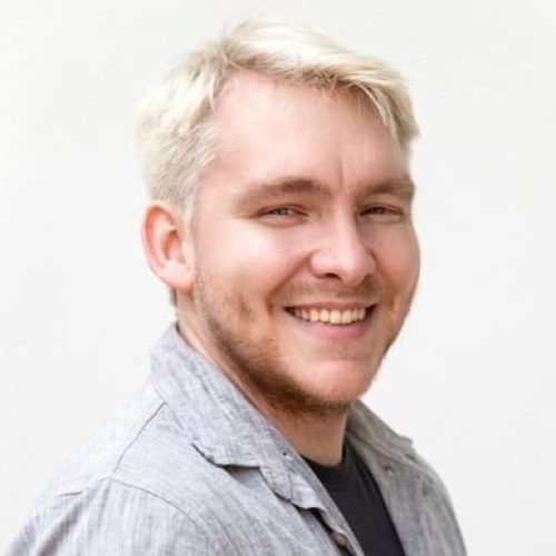 A Man With Blonde Hair Smiling For The Camera.